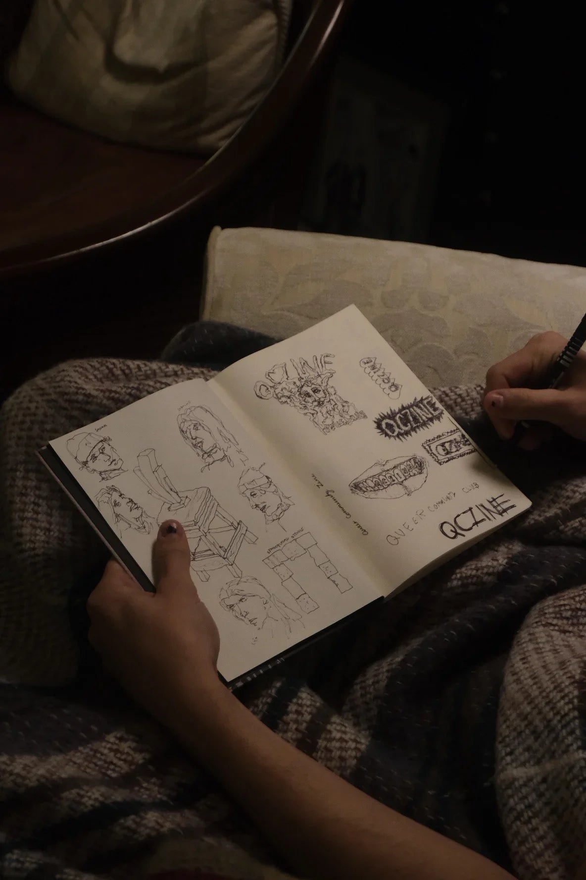 Person sketching original illustrations in a notebook, cozy setting, ethnik stationery