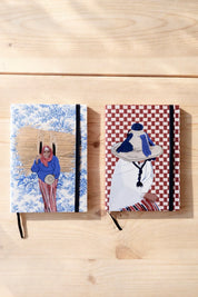 Two ethnik Moroccan notebooks with original illustrated covers on a wooden surface
