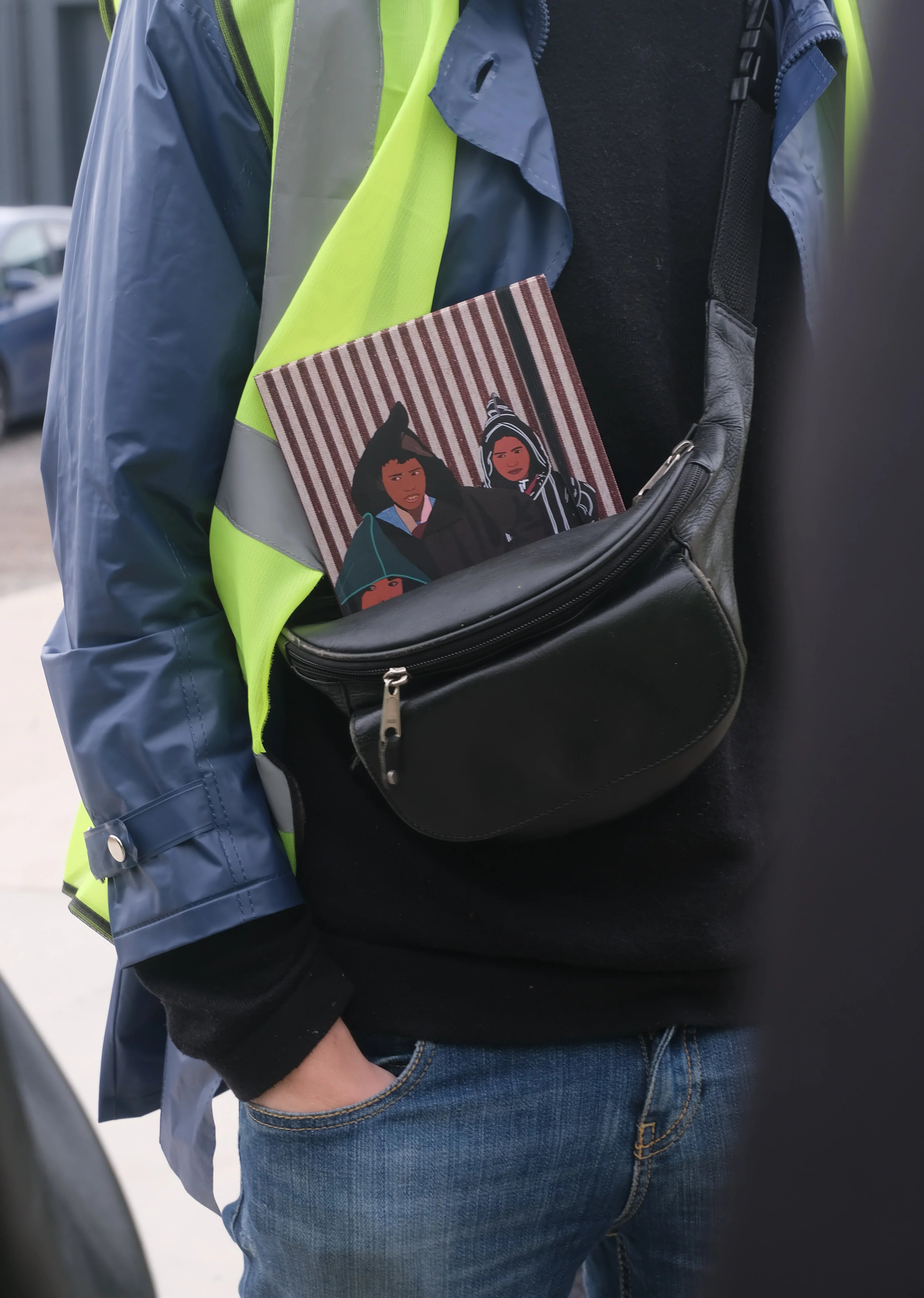 ethnik Moroccan illustrated notebook in black bag, person wearing blue jacket and yellow vest