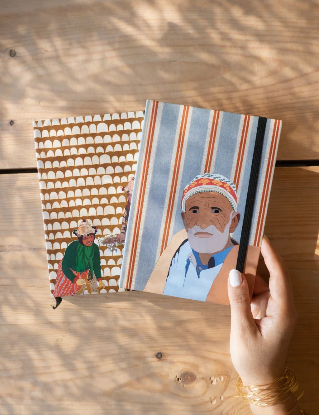 ethnik Moroccan illustrated notebooks on wooden table, hand holding striped cover design