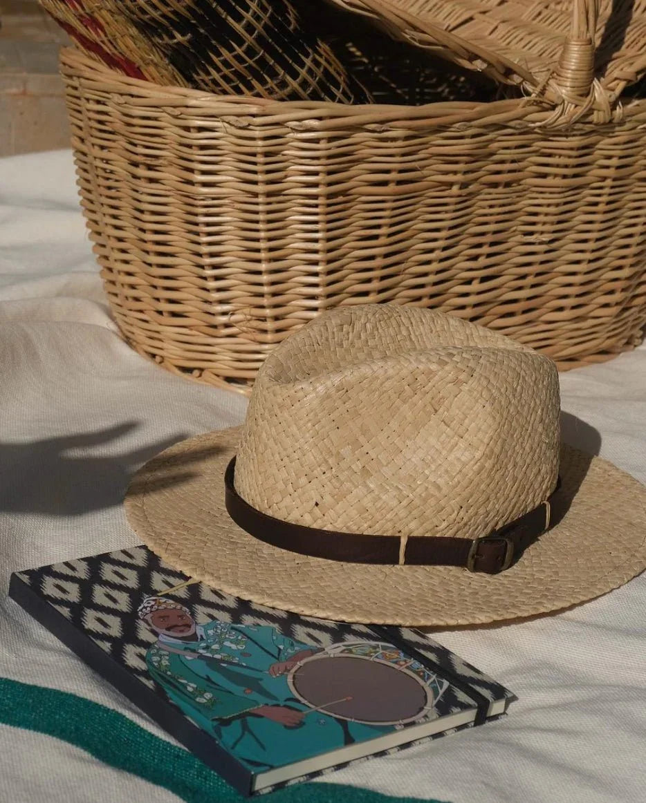 Straw hat and Ethnik notebook with Moroccan illustration on fabric, wicker basket behind