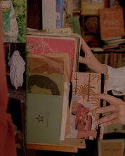 Hand selecting illustrated Moroccan notebook from shelf of vintage books and photos, ethnik stationery.