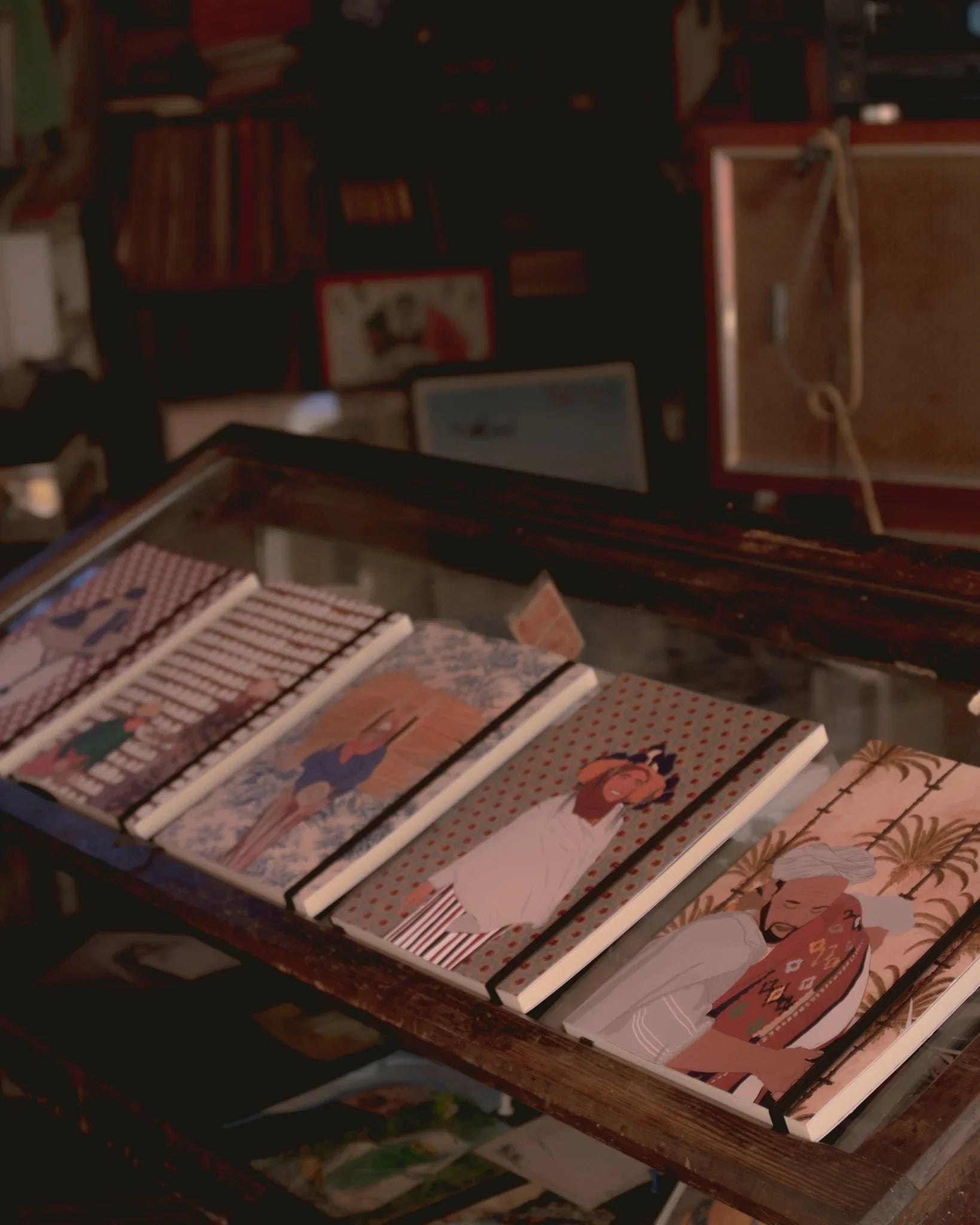 Ethnik Moroccan illustrated notebooks displayed on a glass counter in a cozy shop setting