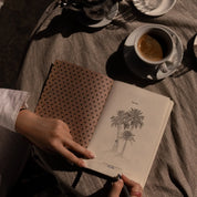 Ethnik Moroccan stationery agenda with palm tree illustration beside coffee on striped tablecloth