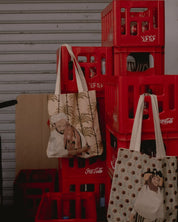 Two ethnik illustrated Moroccan tote bags hanging on red Coca-Cola crates.