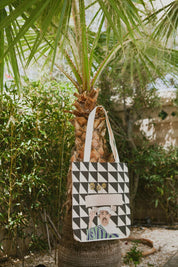 Ethnik Morocco tote bag with geometric black and white pattern and illustrated figure, hanging on palm tree