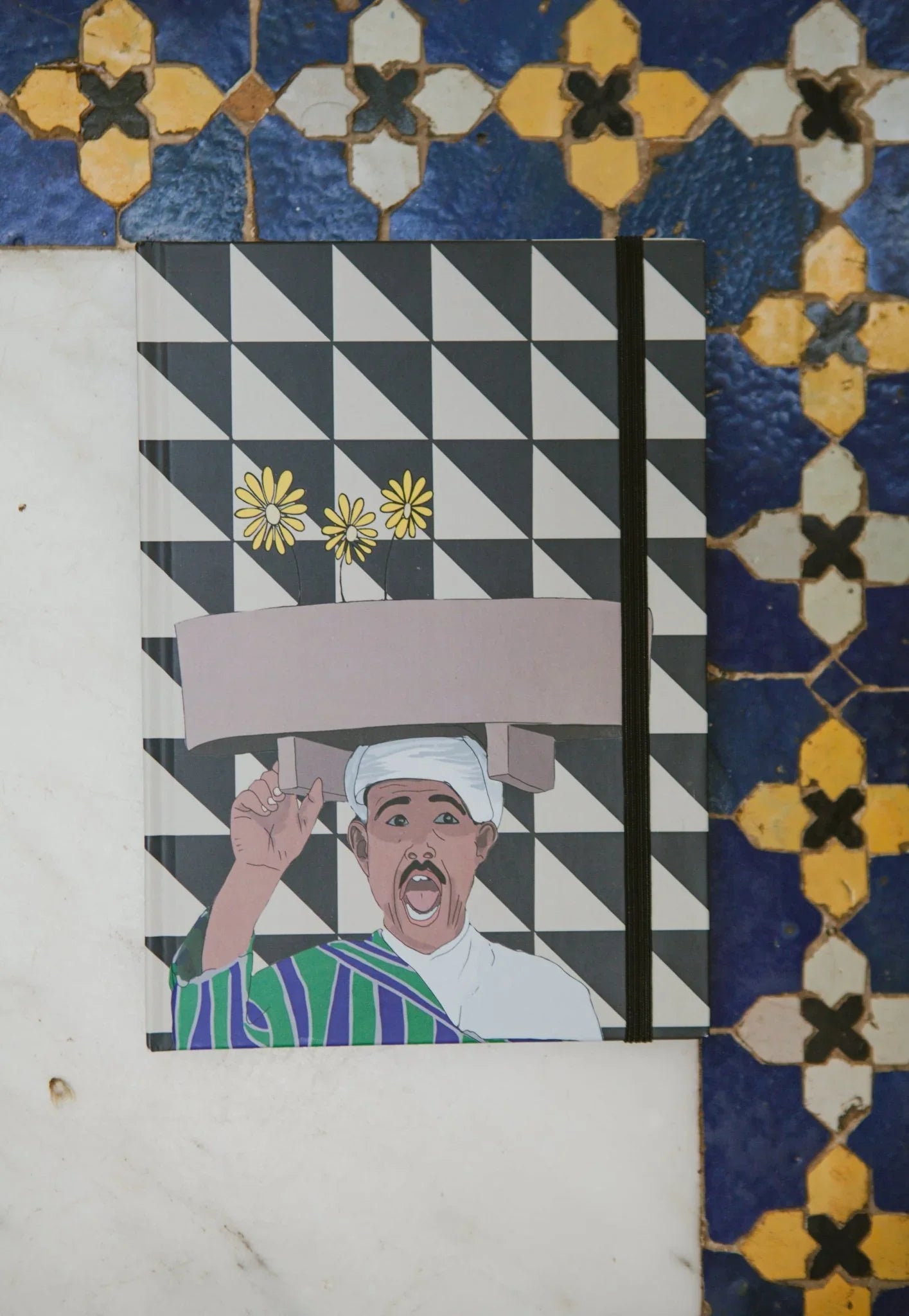 Ethnik illustrated Moroccan notebook with geometric cover on traditional tile floor