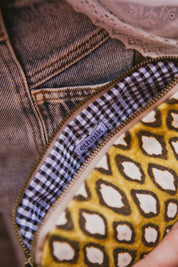 Ethnik patterned pouch with gingham lining, close-up, denim and lace background
