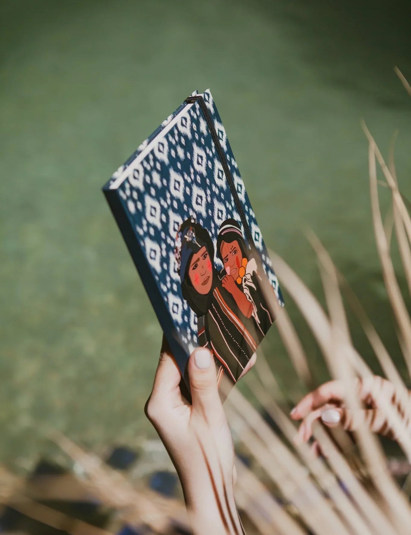 Hand holding ethnik Moroccan stationery notebook with blue geometric pattern and illustrated cover