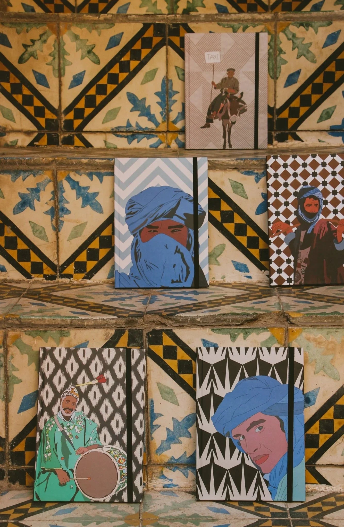 Ethnik Moroccan notebooks with original illustrations displayed on colorful tiled steps