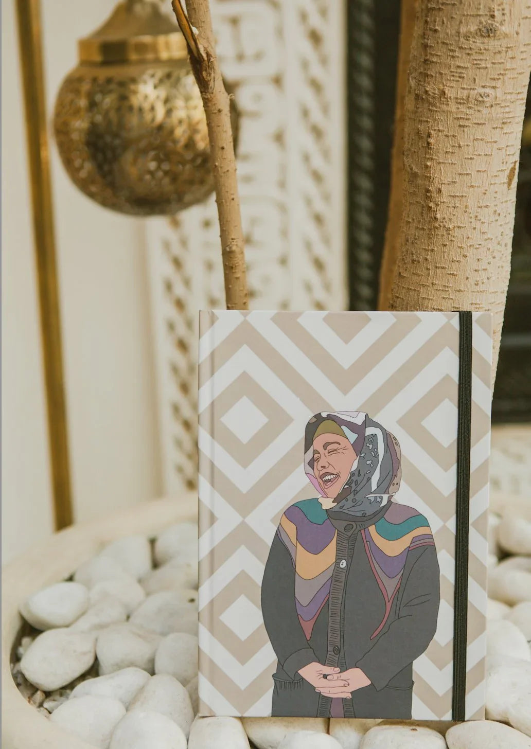 Ethnik Moroccan notebook with geometric pattern and illustrated woman, displayed on white stones