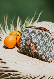 Ethnik Moroccan zip pouch with original illustration, placed on a woven hat near fresh oranges