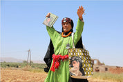 Moroccan woman in traditional dress holding ethnik illustrated notebook and tote bag outdoors