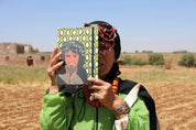 Moroccan woman in traditional clothing holding ethnik illustrated notebook in rural field