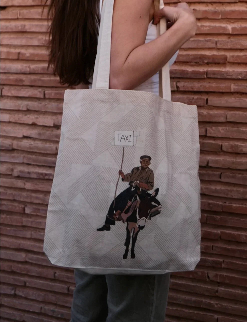 Ethnik tote bag with Moroccan illustration of man on donkey holding 'TAXI' sign, outdoor setting