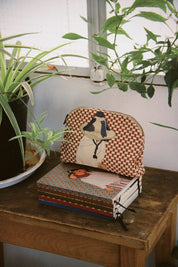 Ethnik Moroccan pouch with illustration and handmade journals on wooden table, surrounded by plants