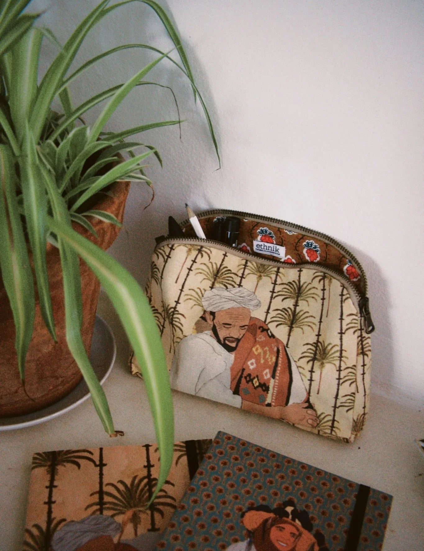 ethnik Moroccan stationery and pouch with original illustrated designs on a desk next to a plant