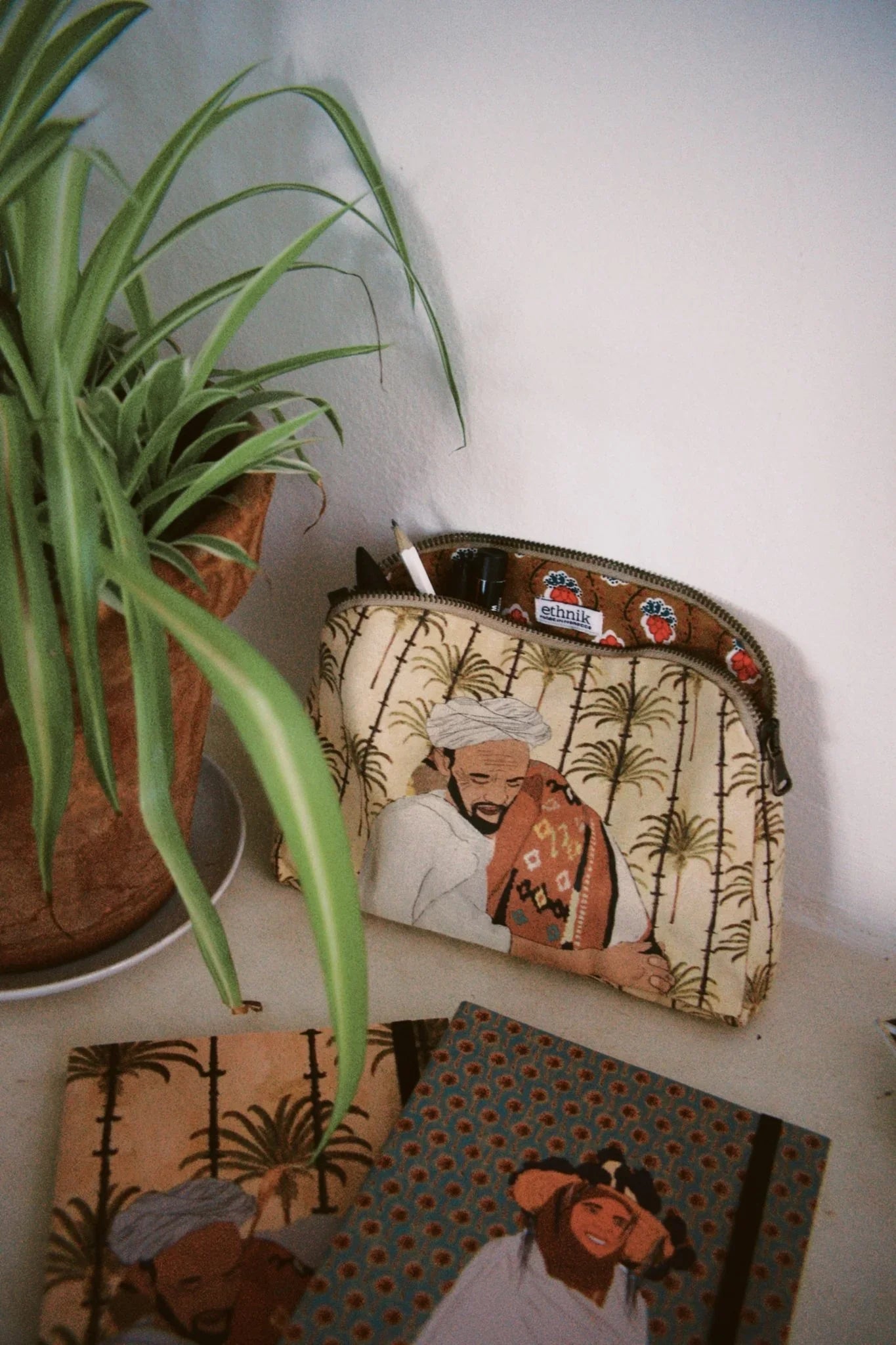 ethnik Moroccan stationery and pouch with original illustrated designs on a desk next to a plant