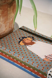 Moroccan illustrated ethnik notebook with patterned cover beside clay pot and green plant
