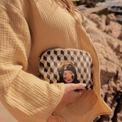 Woman holds geometric ethnik pouch with Moroccan illustrated face, outdoor setting