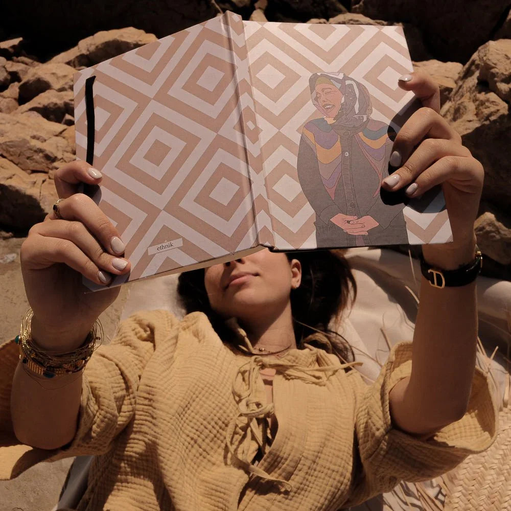 Woman relaxing outdoors holding ethnik Morocco notebook with geometric cover and unique illustration