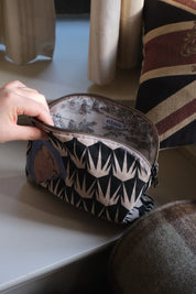 Ethnik patterned zipper pouch with original illustration, handmade in Morocco, on table by pillows.